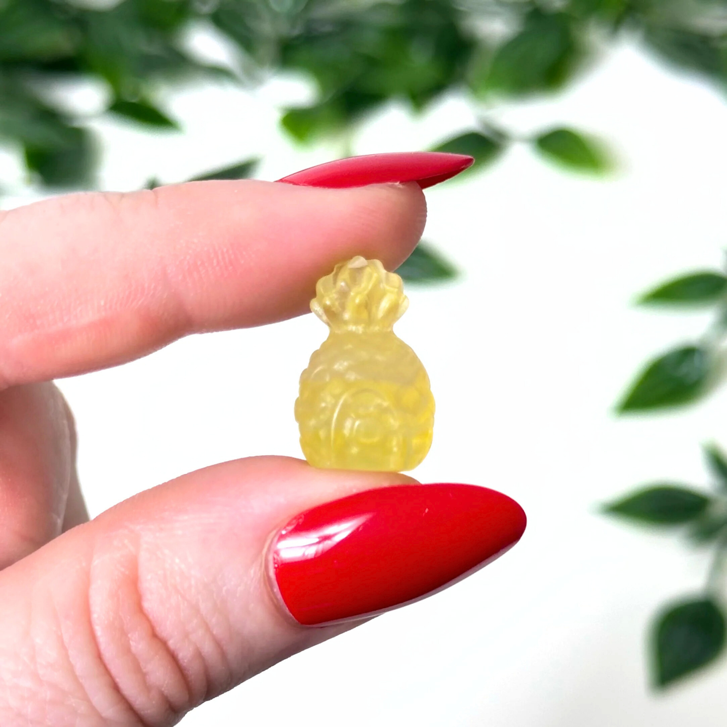 Hand holding a mini fluorite crystal carving on a white background