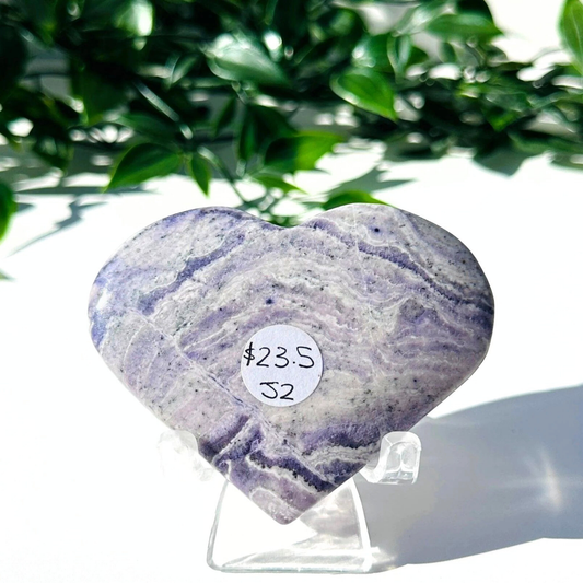 Purple fluorite and white chalcedony crystal heart on stand with a white leafy background