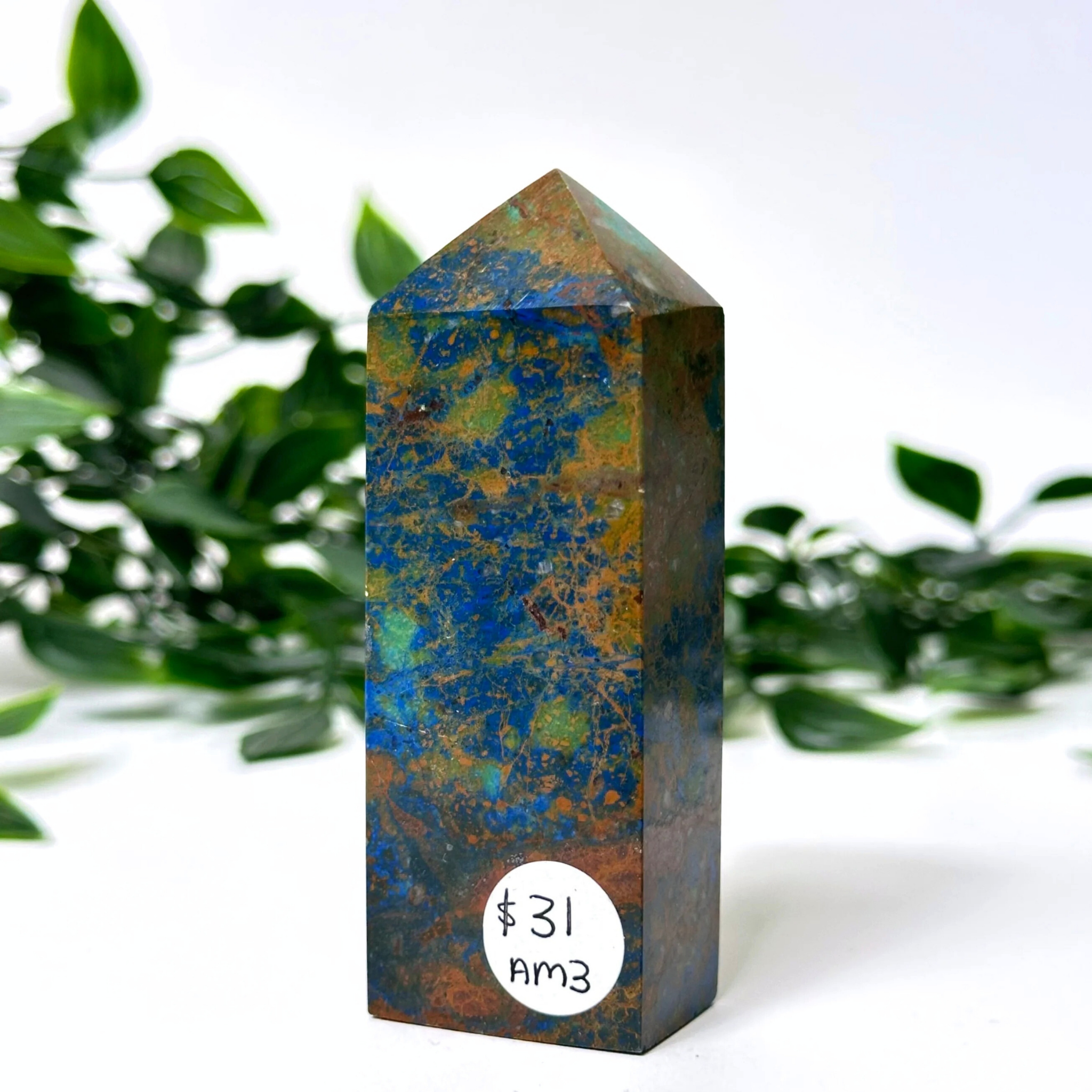 Marbled blue crytstal tower with a price tag against a green leafy background