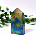 Azurite malachite crystal tower on a white and leafy background.