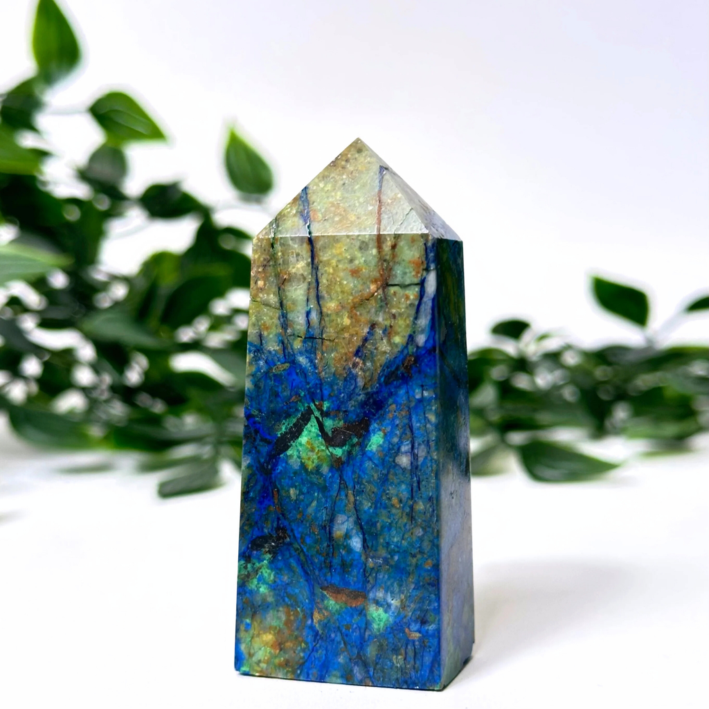 Multicolored crystal tower with a natural green leafy background
