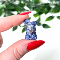 Hand holding a mini jasper crystal carving on a white background