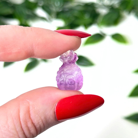 Hand holding a mini fluorite crystal carving on a white background