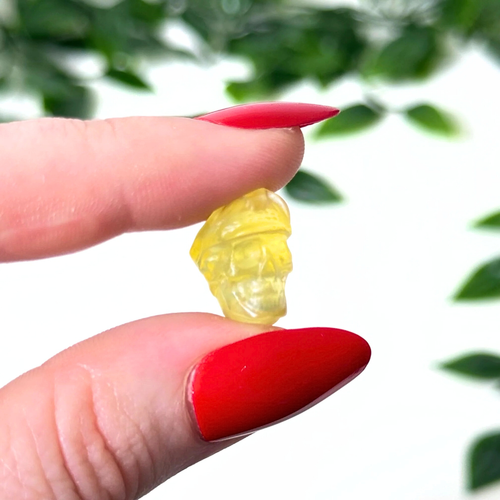 Hand holding a mini fluorite crystal carving on a white background