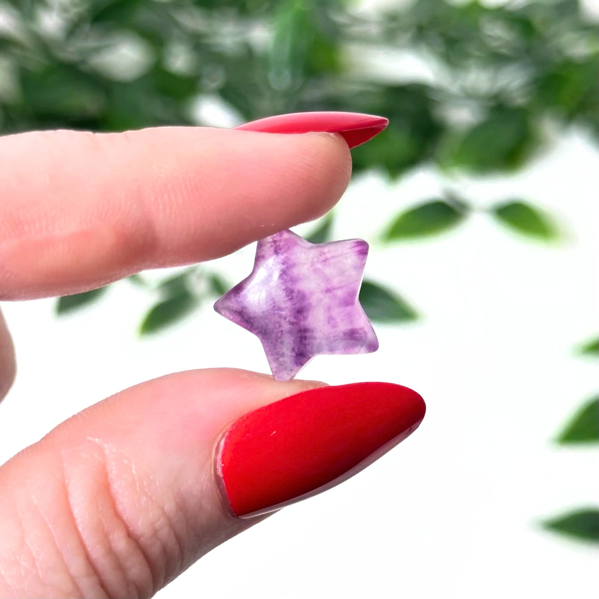 Hand holding a mini fluorite crystal carving on a white background