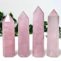 4 rose quartz crystal towers in front of a white and leafy background