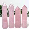 4 rose quartz crystal towers in front of a white and leafy background