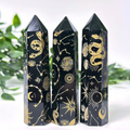 Three Black Obsidian crystal towers with gold astrological symbols on a white background