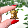 Hand holding a small tigers eye tombstone crystal on a white leafy background