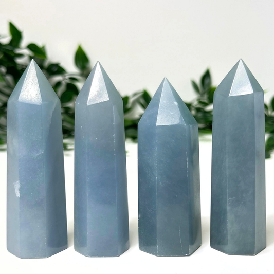 4 angelite crystal towers in front of a white and leafy background