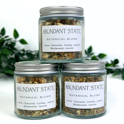 Three jars of Abundant State Botanical Blend on a white background with greenery.