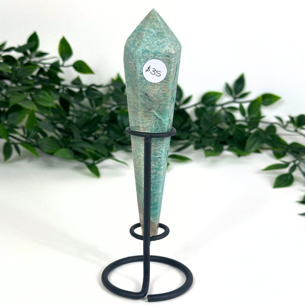 Amazonite crystal on a stand with greenery in the background
