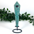 Teal amazonite crystal on a stand with greenery in the background