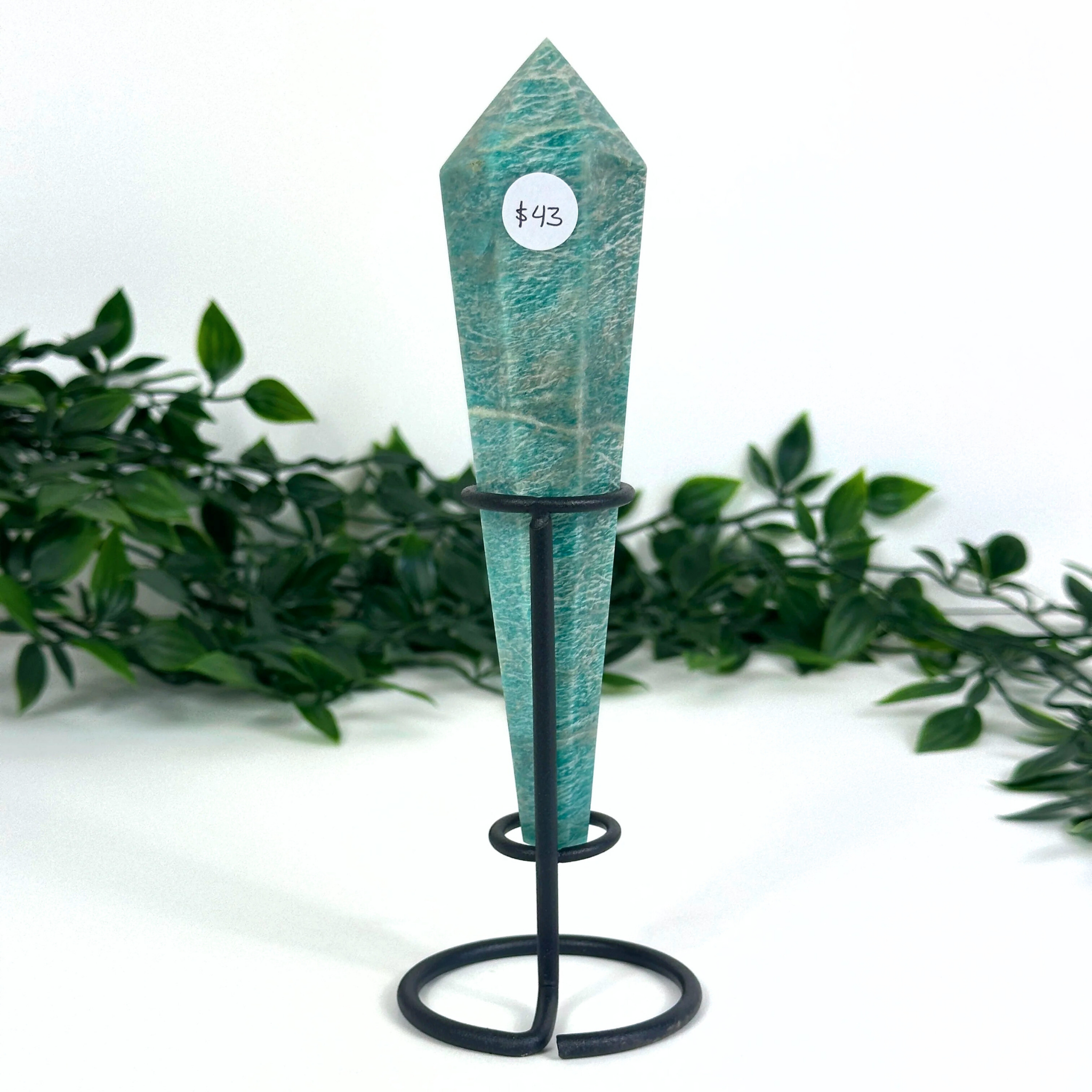 Teal amazonite crystal on a stand with a price tag against a white background