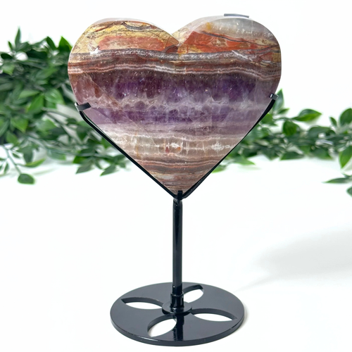 Heart-shaped amethyst crystal on a stand with a natural background
