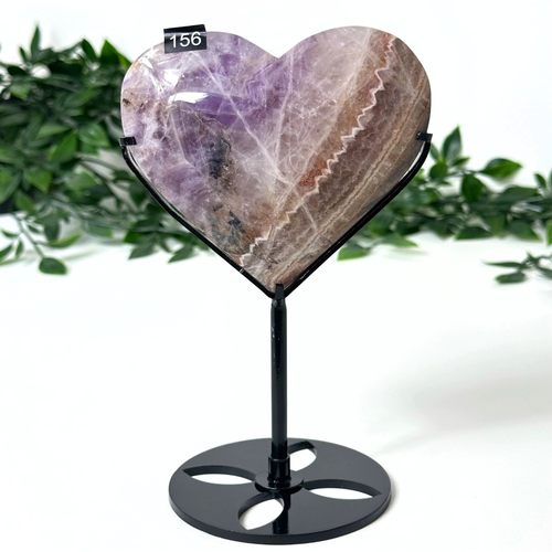 Heart-shaped amethyst on a stand with a green leafy background