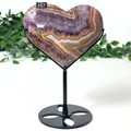 Heart-shaped amethyst stone on a stand with a white background