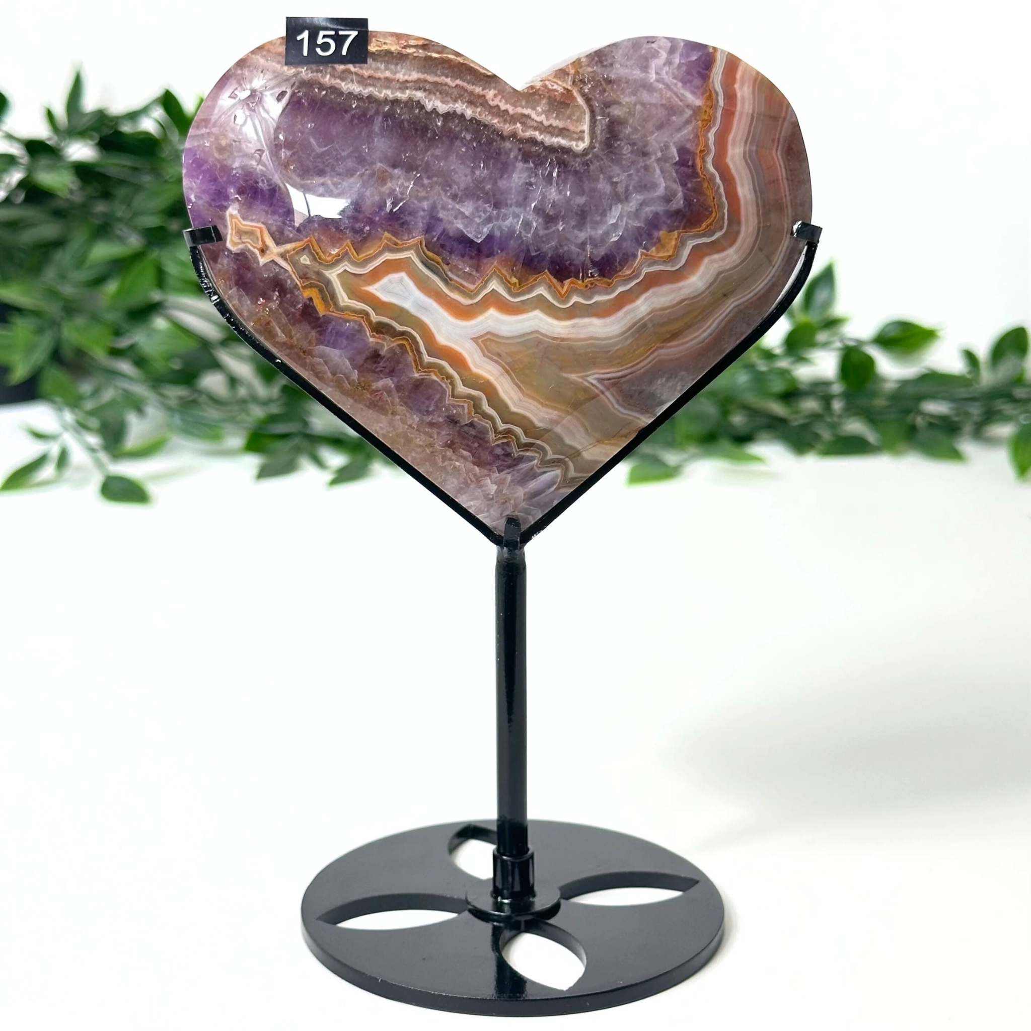 Heart-shaped amethyst stone on a stand with a white background