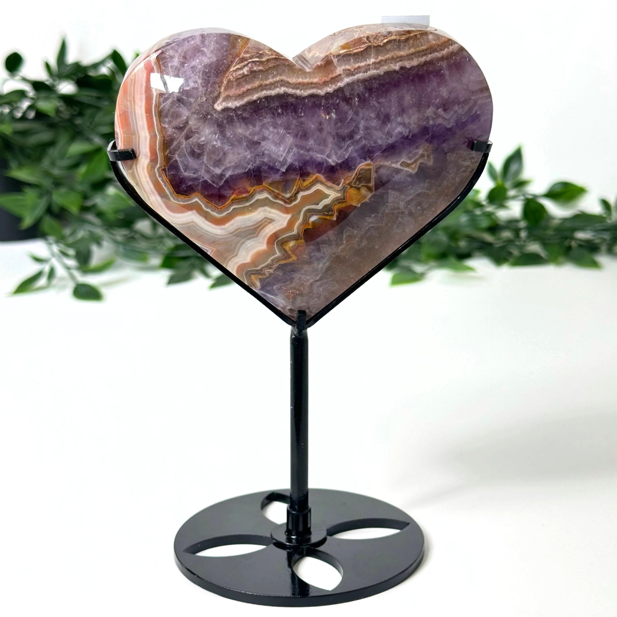 Heart-shaped amethyst stone on a stand with a white background