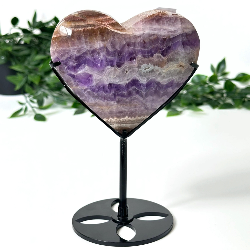 Heart-shaped amethyst crystal on a black stand with a white background