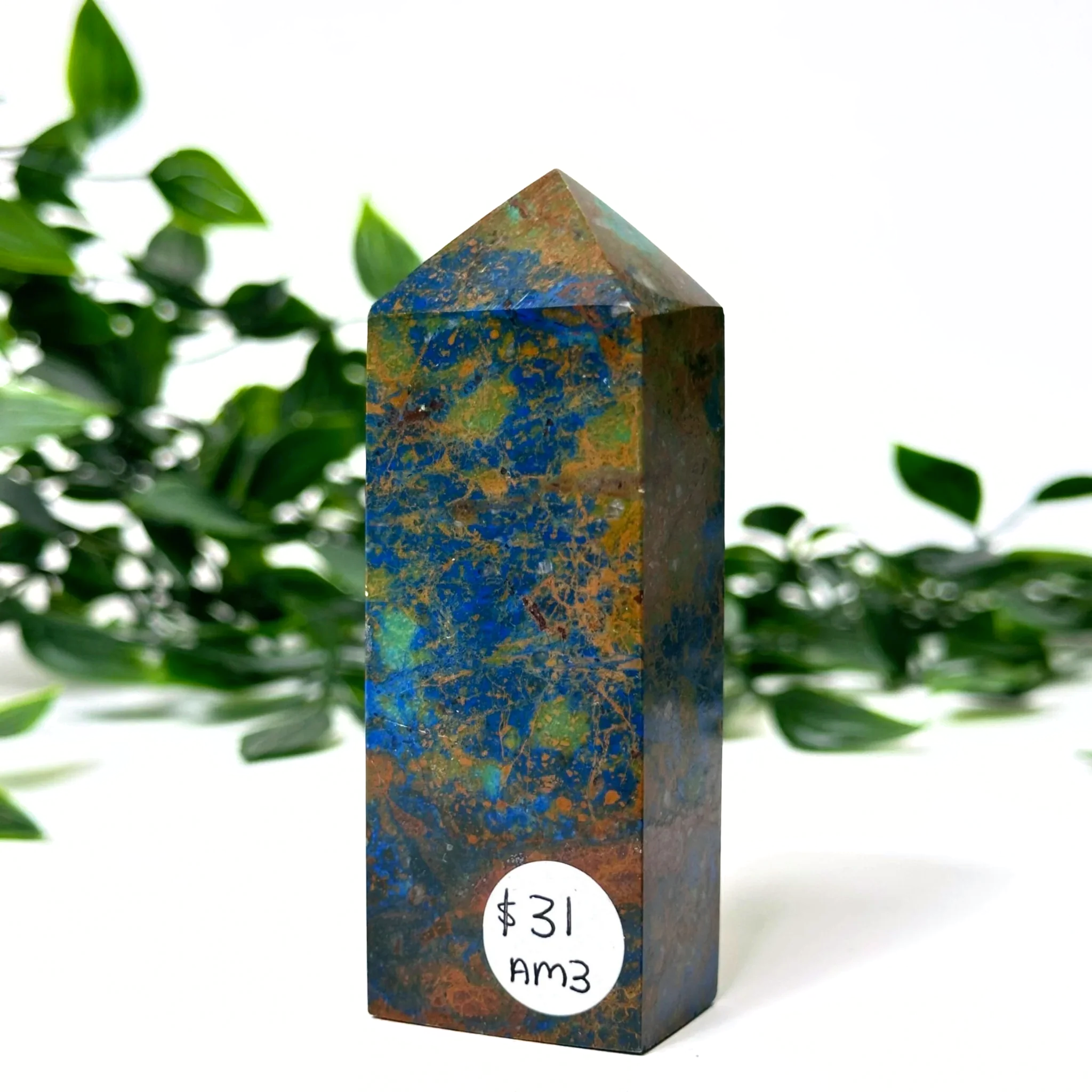 Azurite and malachite crystal tower with a price tag label against a green leafy background