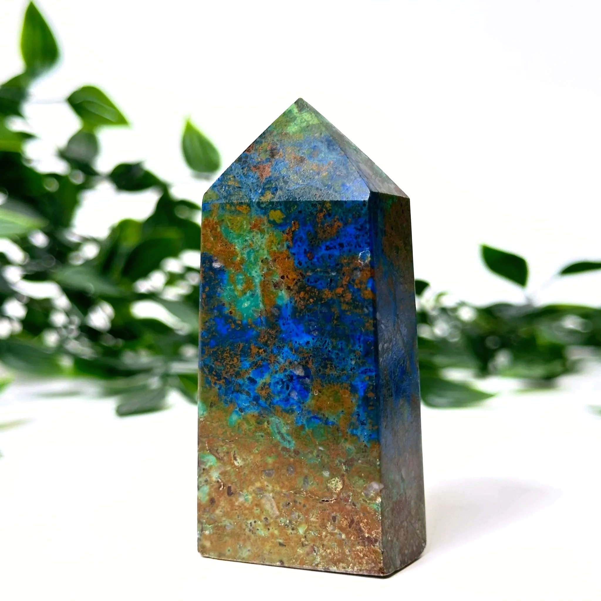 Azurite and malachite crystal tower with a natural green leafy background