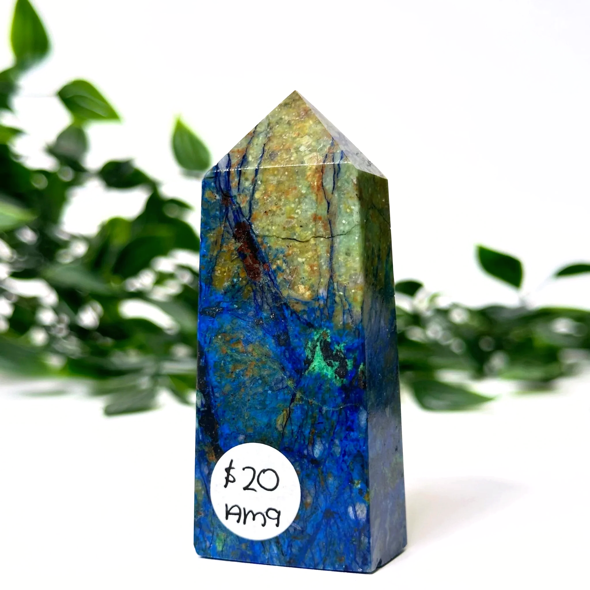 Azurite and malachite crystal tower with a price tag label against a green leafy background