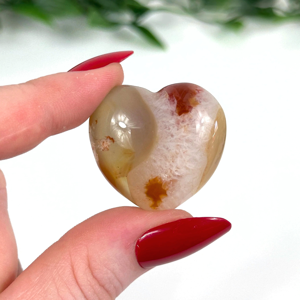 Carnelian crystal heart held in front of white background