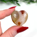 Carnelian crystal heart held in front of white background
