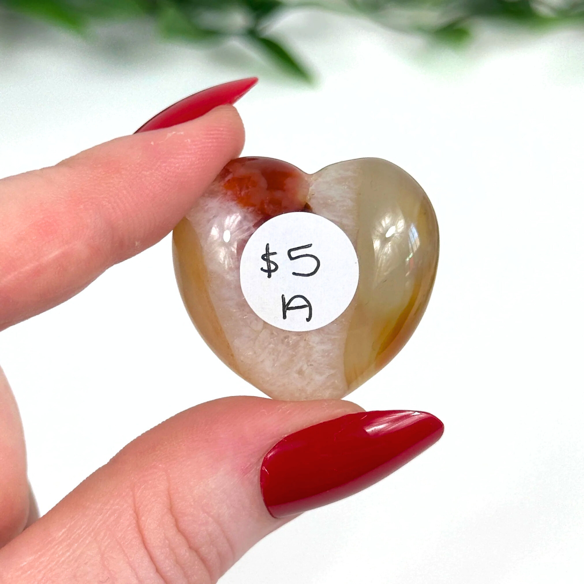 Carnelian crystal heart held in front of white background
