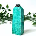 Chrysocolla crystal tower with a black tag displaying the number 56, set against a white background with green leaves.