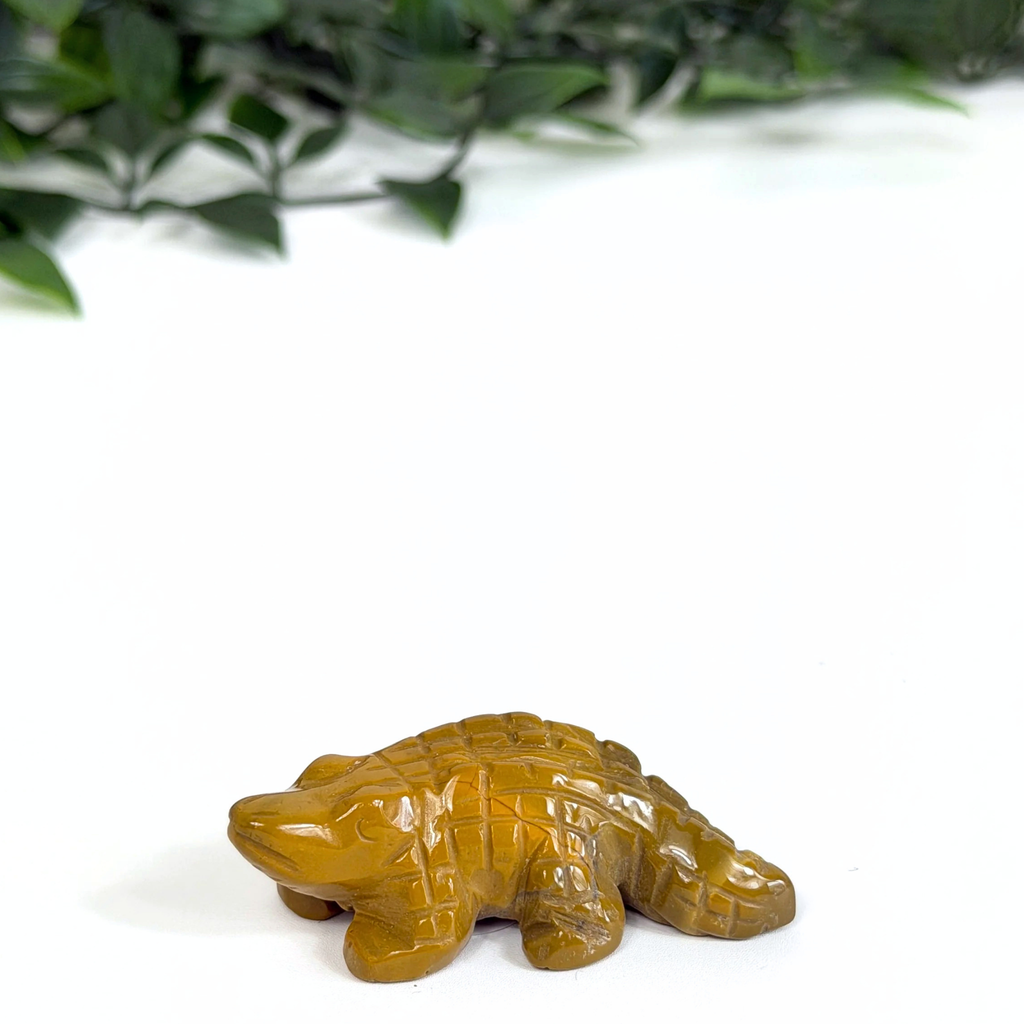 Mookaite crocodile carving on a white background with green leaves in the corner