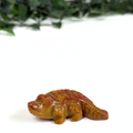 Mookaite crocodile carving on a white background with greenery in the background