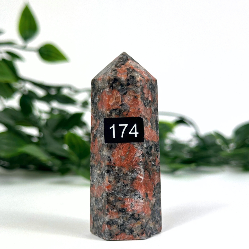 Feldspar crystal tower with orange and grey patterns on a white background