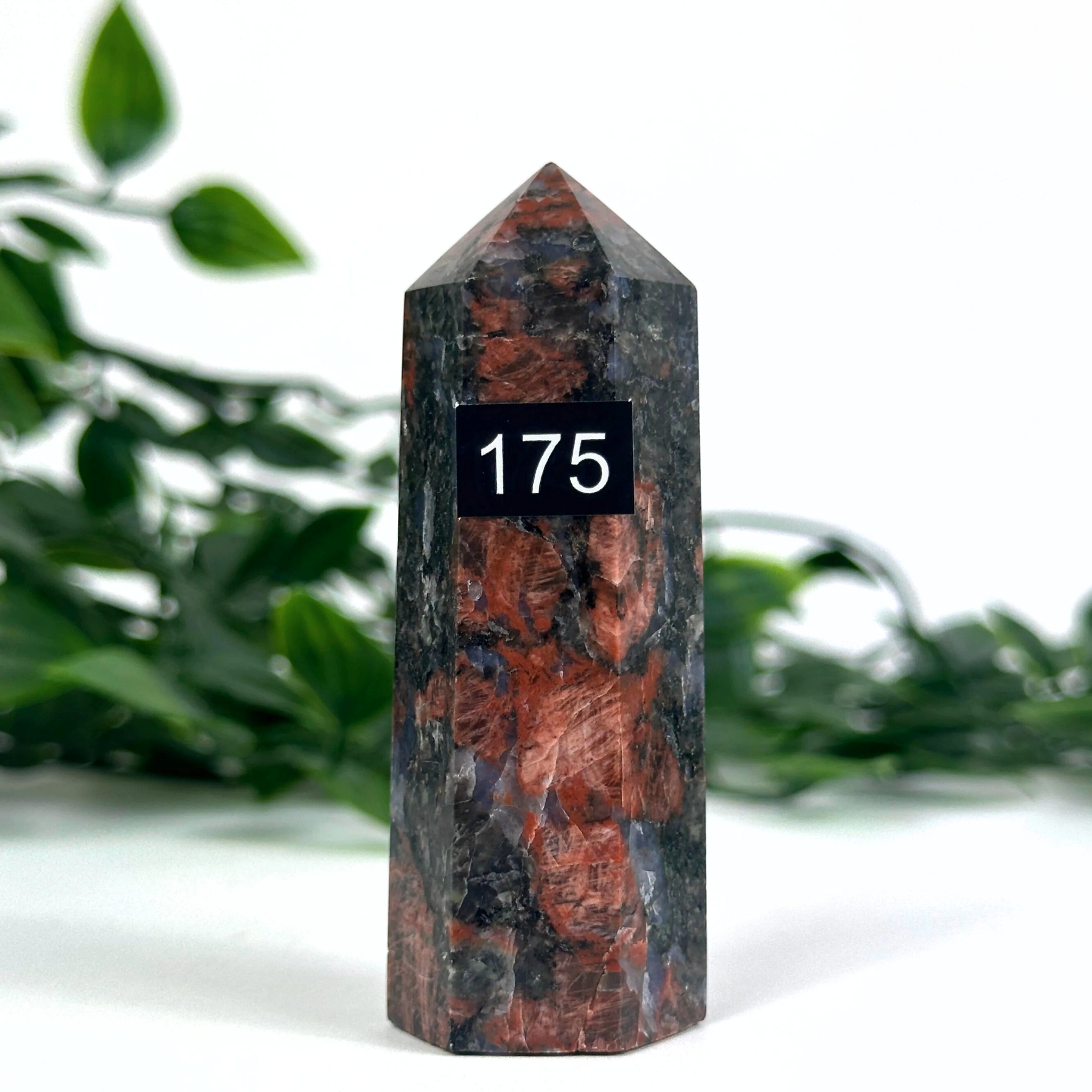 Feldspar crystal tower against a green leafy background