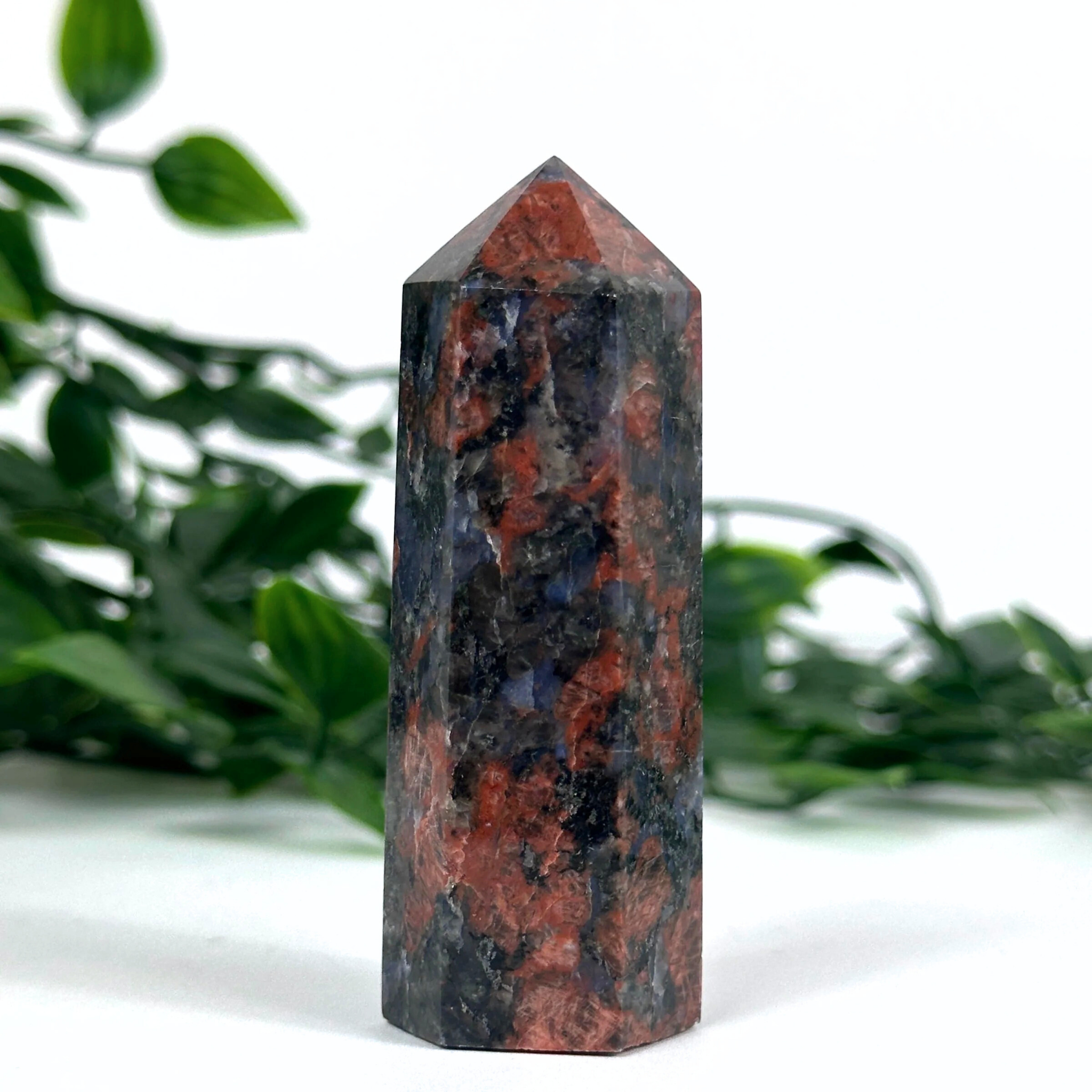 Feldspar crystal tower with green leaves in the background