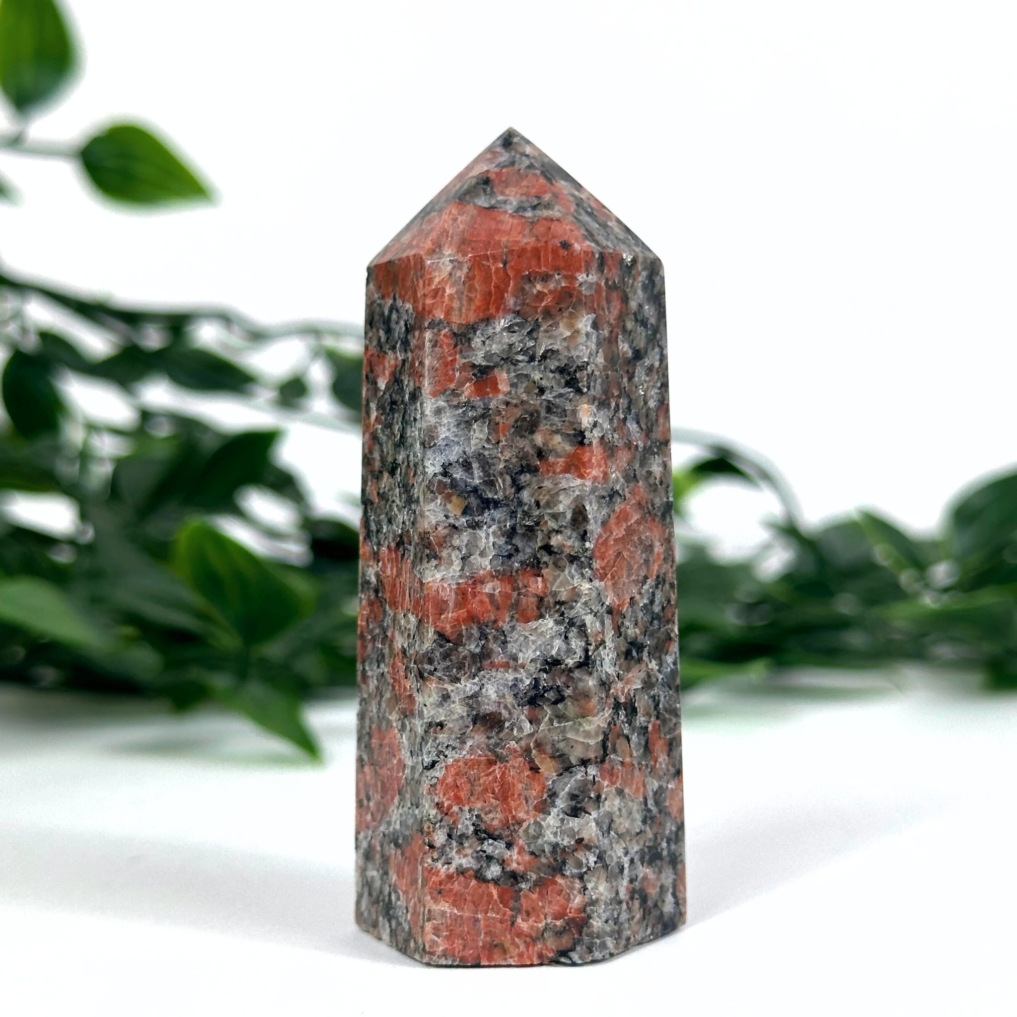 Feldspar crystal tower with red and gray patterns on a white background