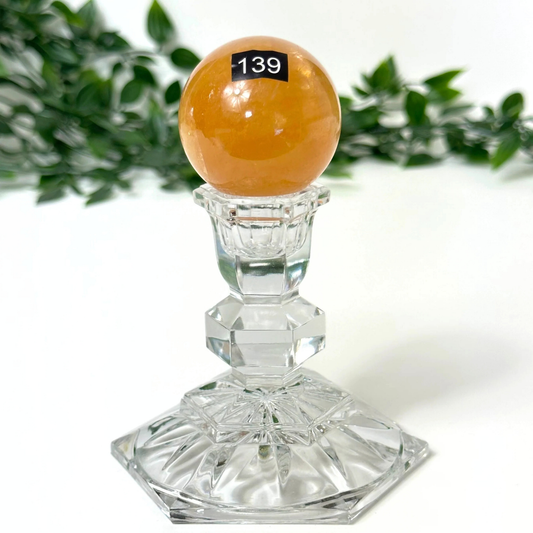 Crystal candle holder with a honey calcite sphere on a white background