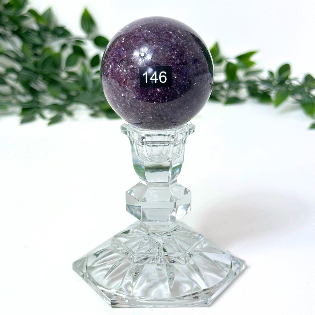 Lepidolite crystal sphere on a crystal stand against a white background