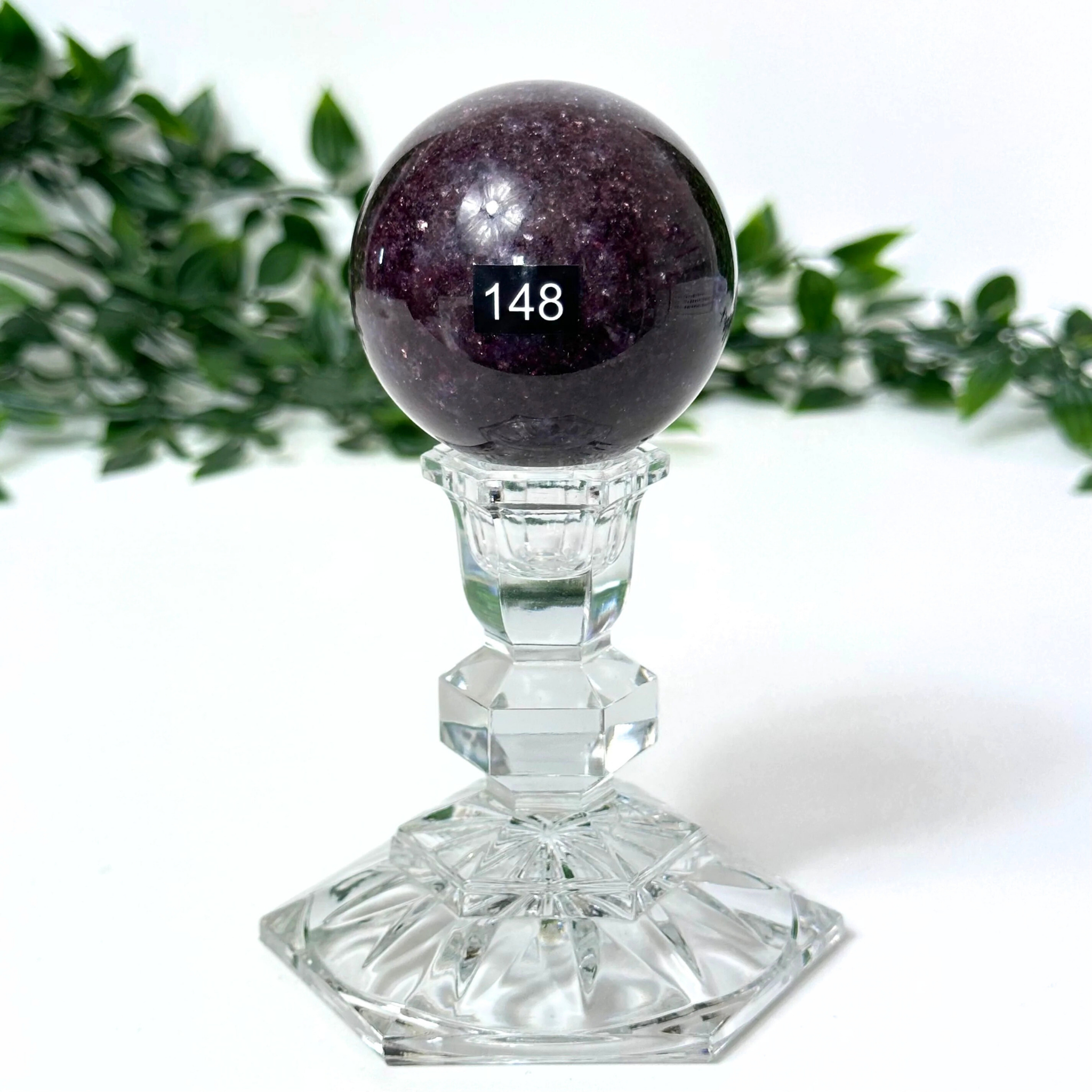 Lepidolite crystal ball with a stand on a white background