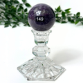 Crystal pedestal with a purple lepidolite sphere against a white background