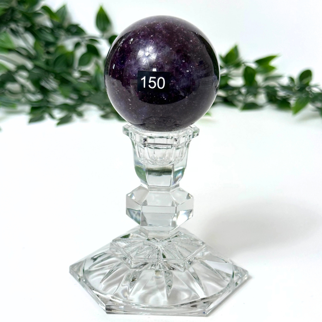 Lepidolite crystal sphere on a crystal stand against a white background