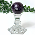 Lepidolite crystal sphere on a crystal stand against a white background