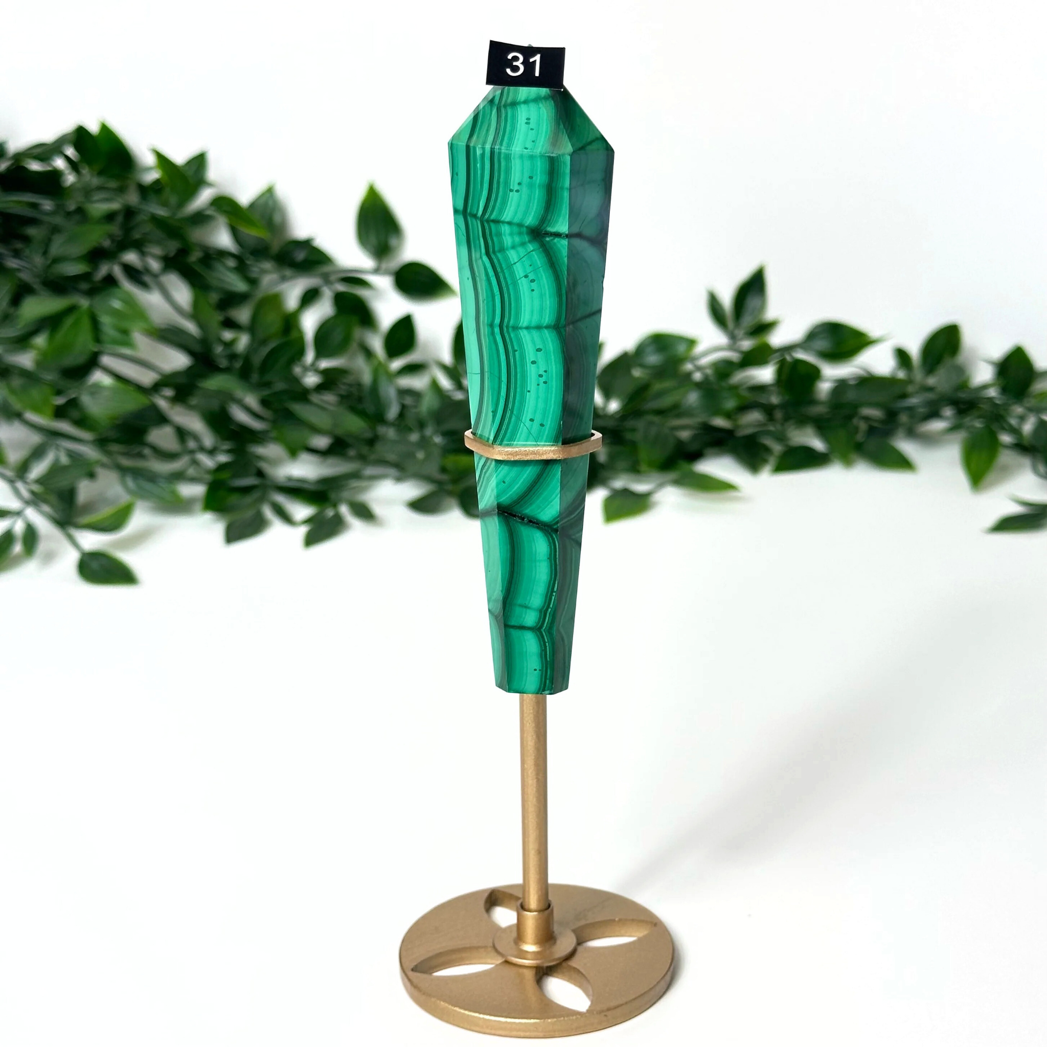 Decorative malachite crystal and gold stand on a white background