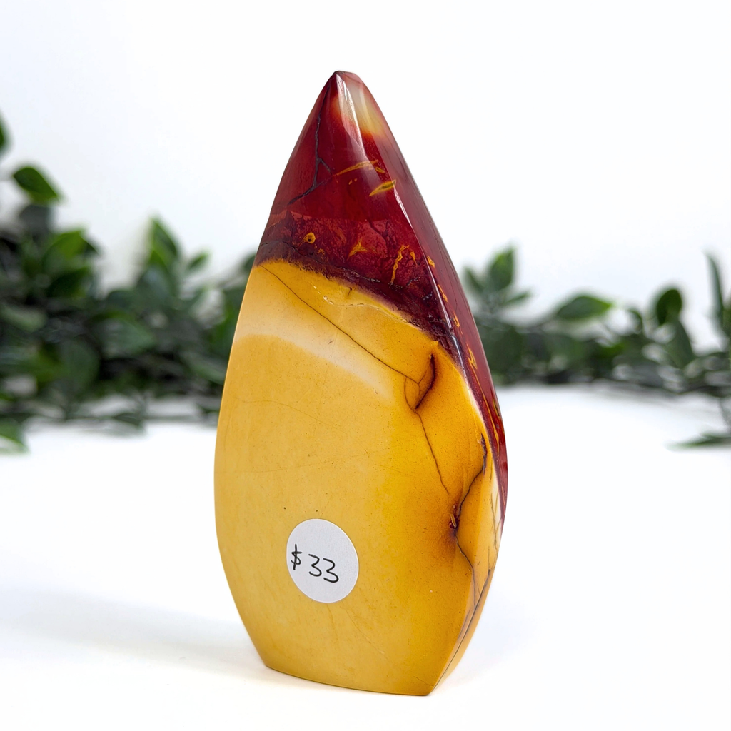 Mookaite crystal teardrop carving with a white leafy background