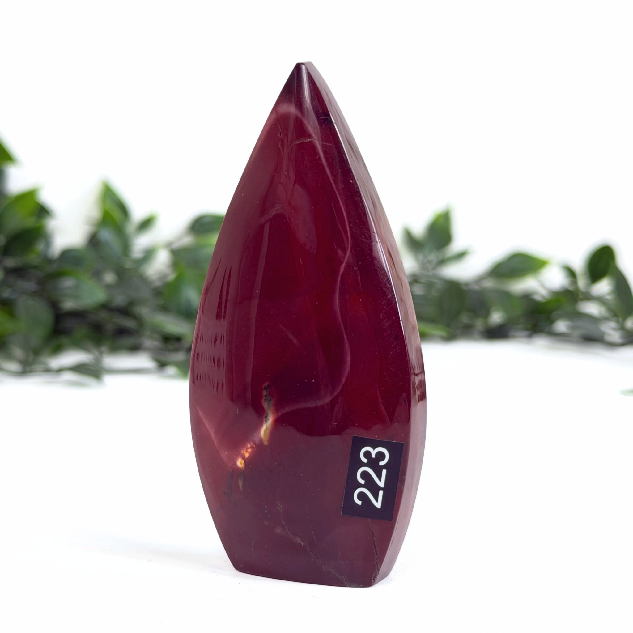Teardrop-shaped red mookaite crystal with '223' on a white background