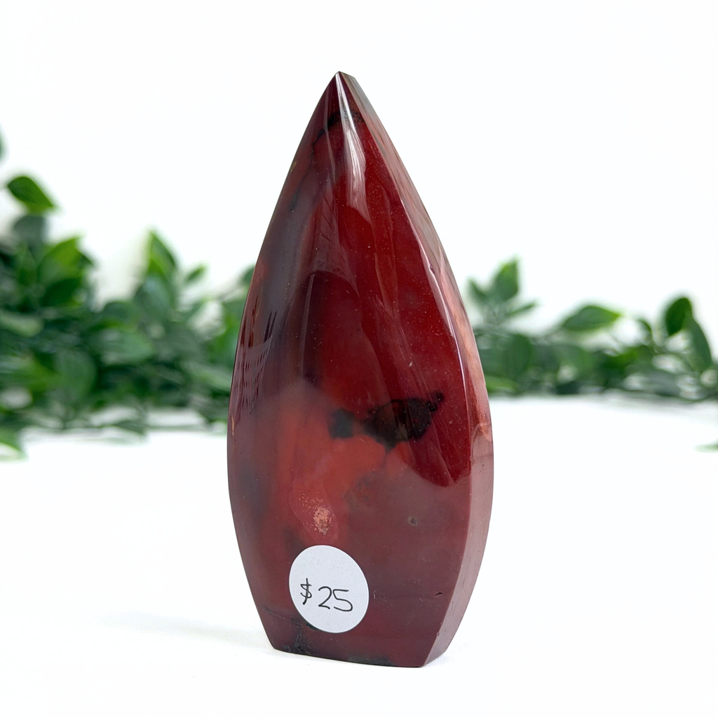 Red teardrop-shaped mookaite crystal with a white label on a white background