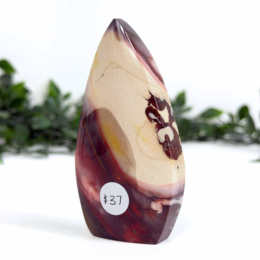 Marbled mookaite stone with a price tag on a white background
