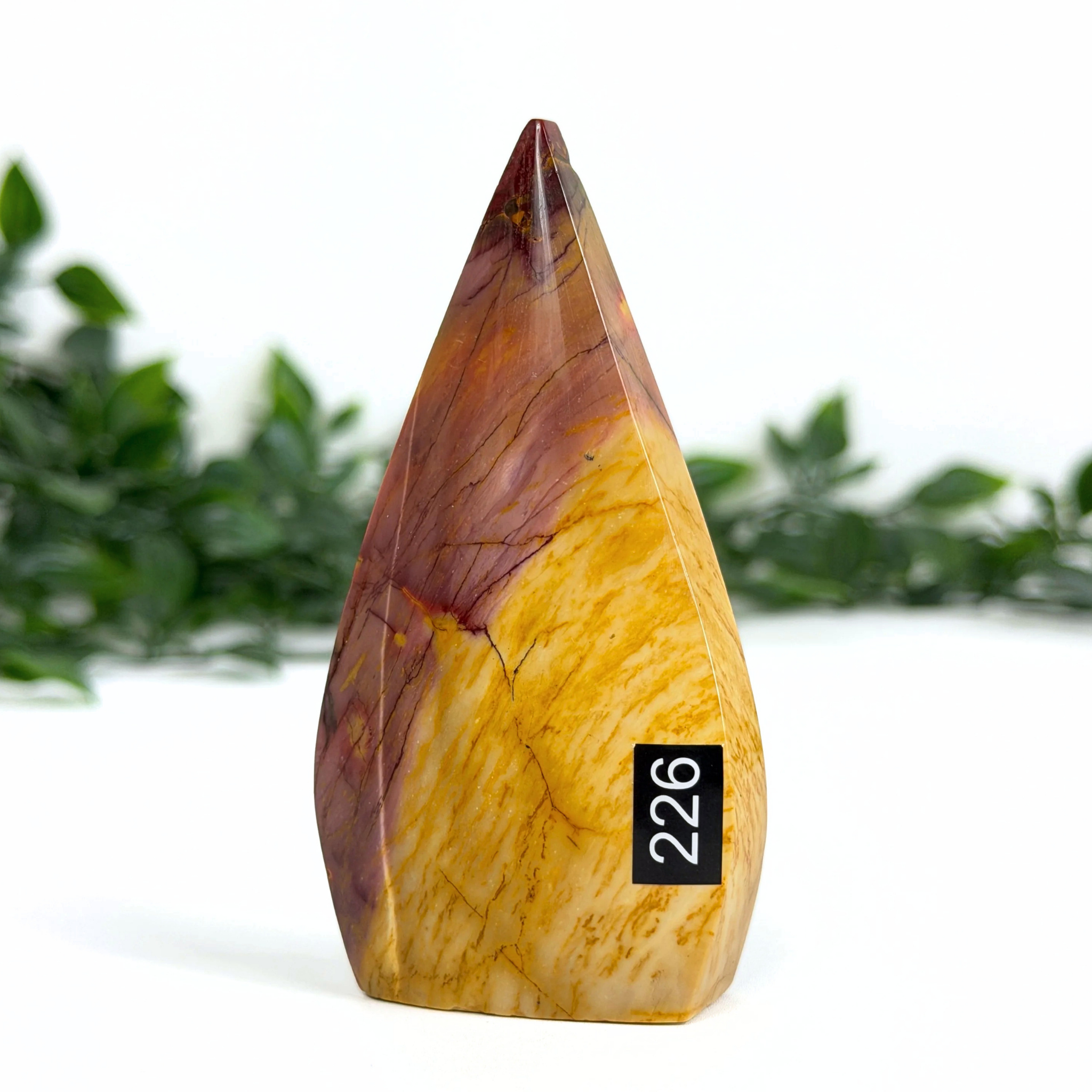 Teardrop-shaped mookaite stone with a black label on a white background