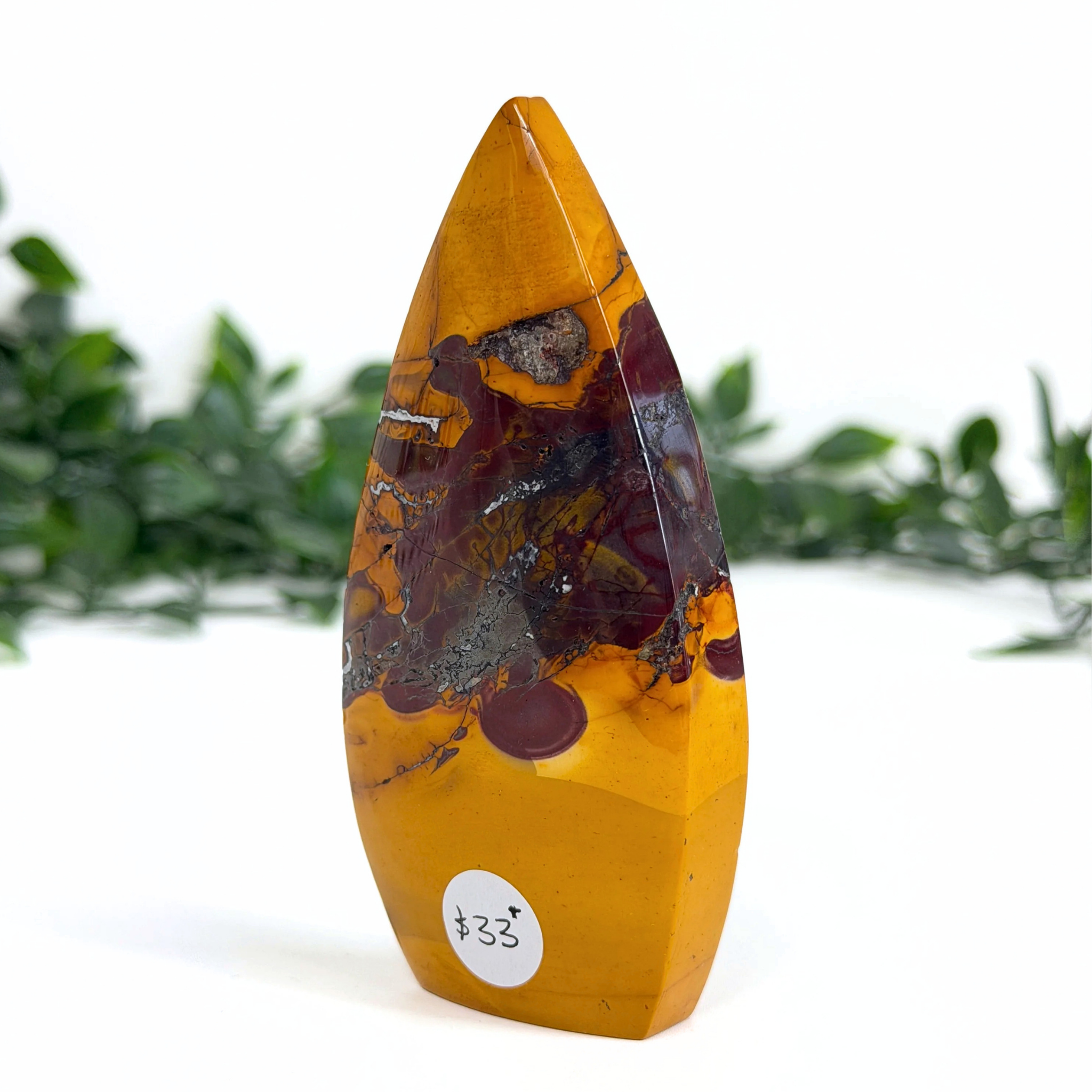 Mookaite crystal teardrop carving with a label on a white background